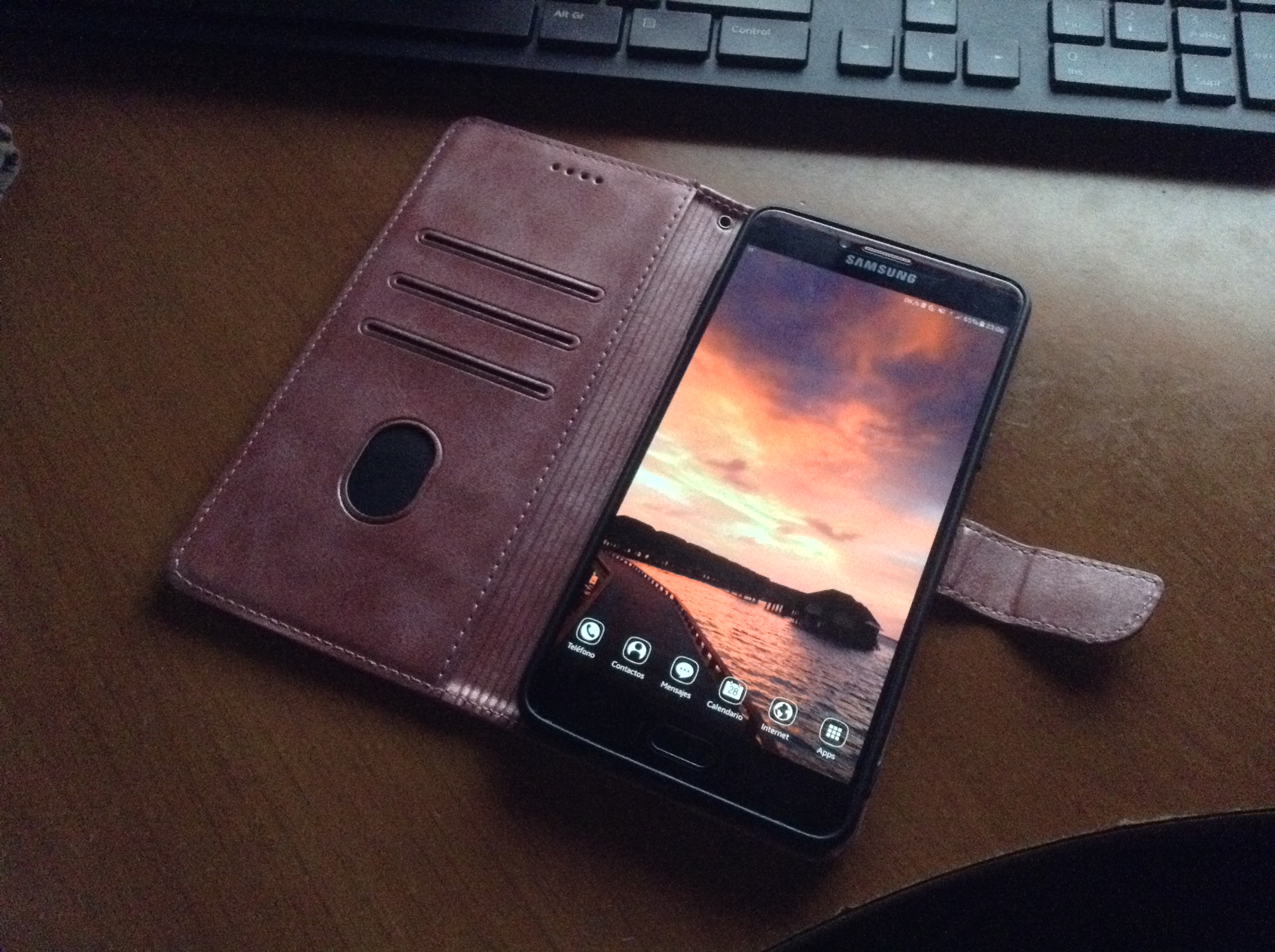 a image showing the phone entirely, the phone is a galaxy c9 pro in black and it has a pink book-style case on with a pinkish sunset on a bridge as the wallpaper