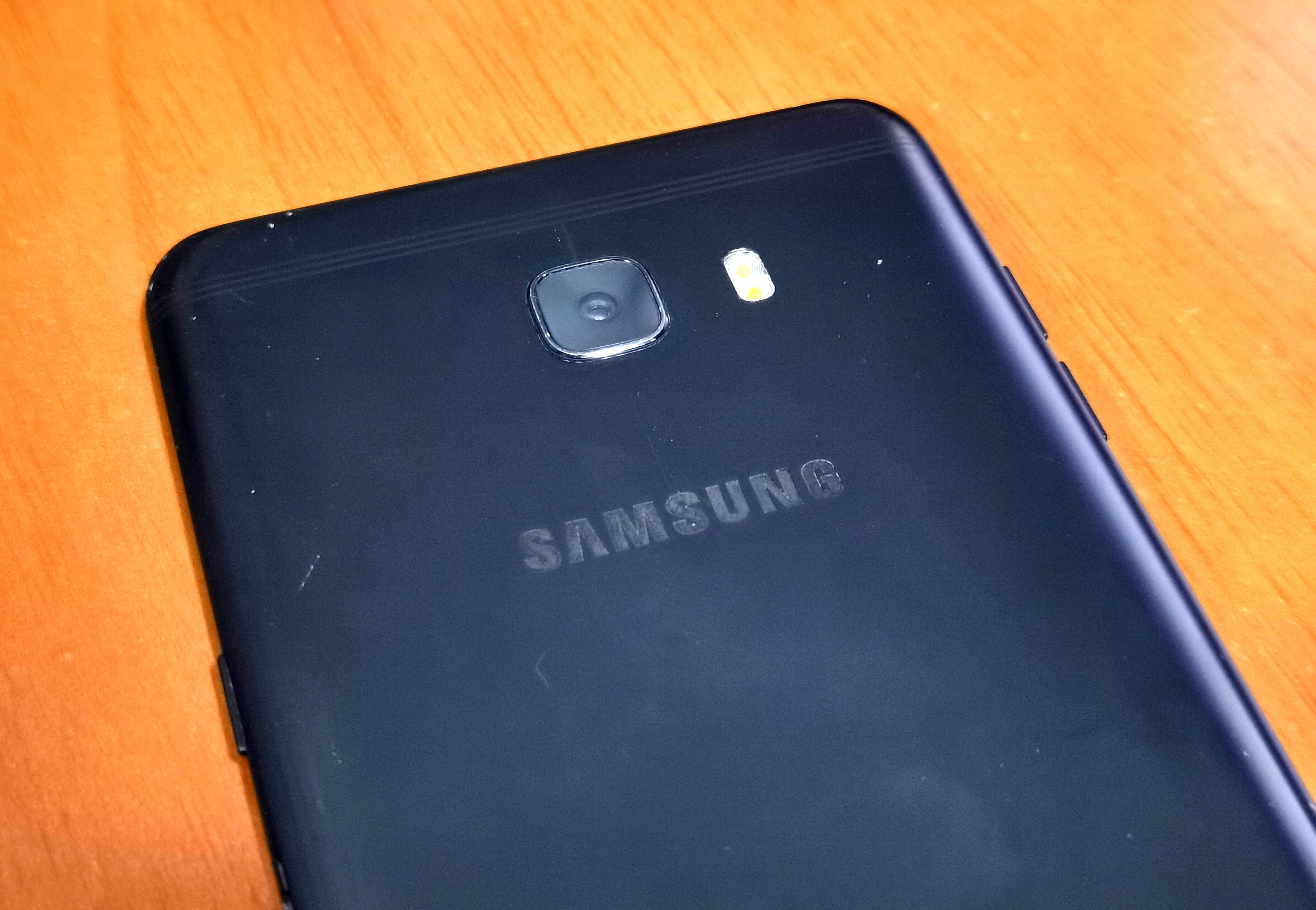 a closeup of the back of the phone focusing on the top part, showing some white dots and scratches where the paint has wore off